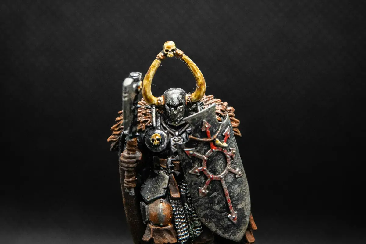 A painted armoured warrior miniature with worn metal armour on a dark background