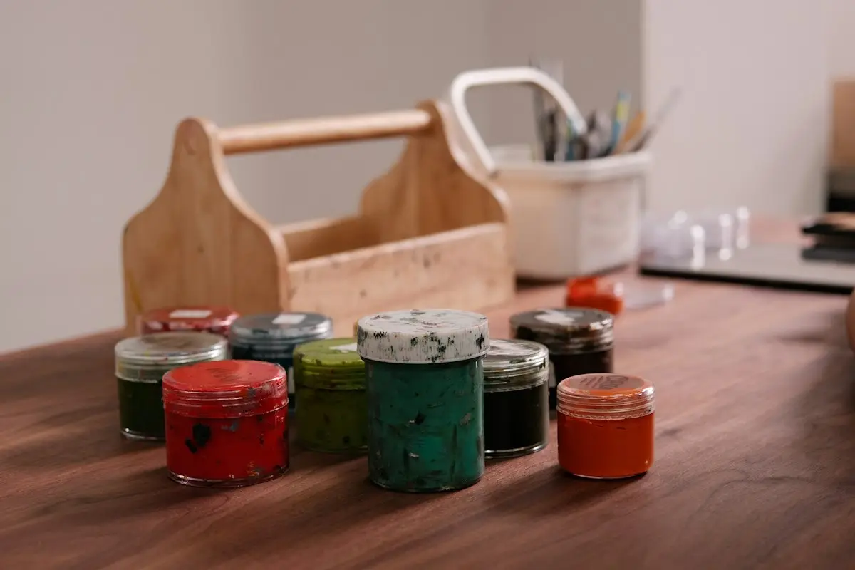 Colourful paint jars and art supplies on a wooden table